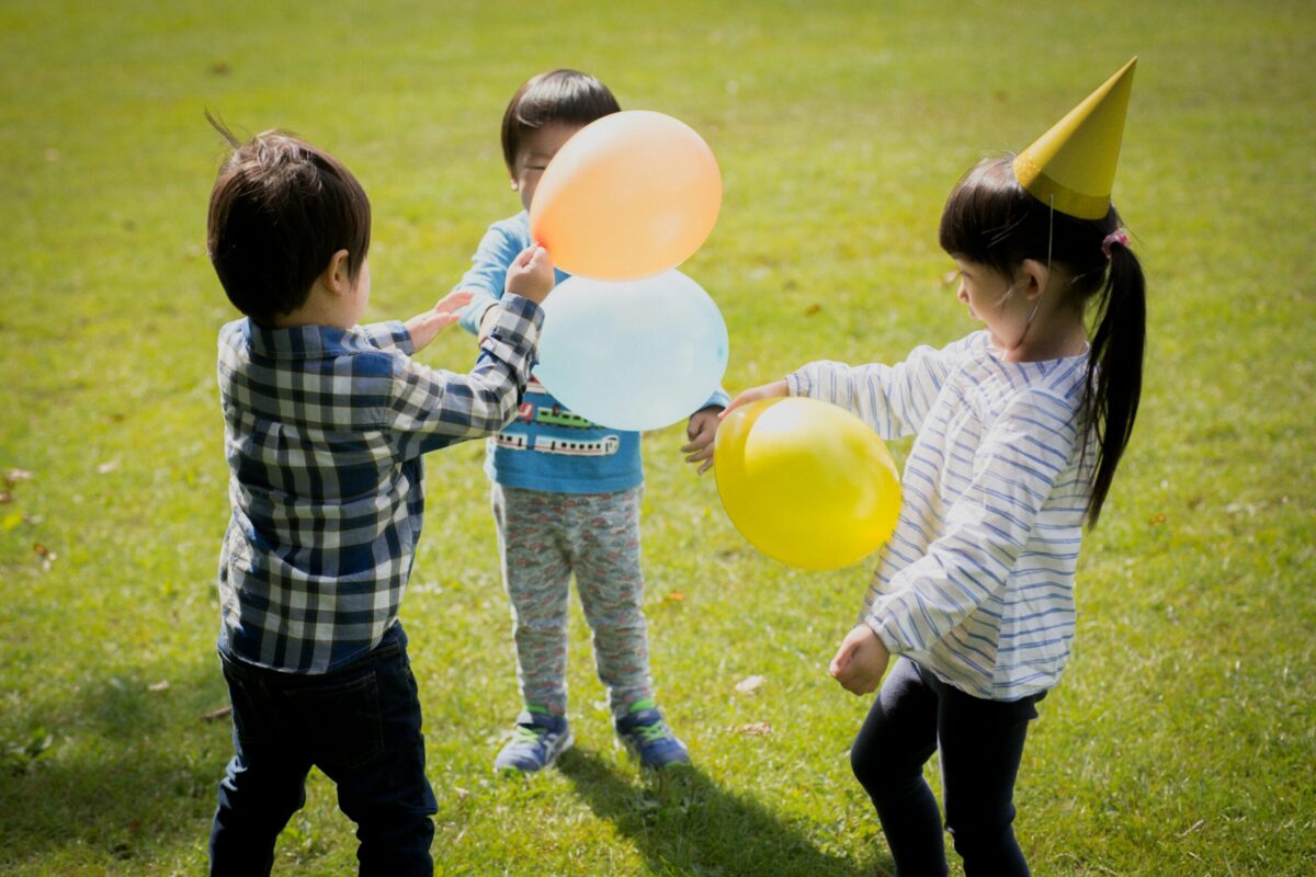 Three children playing with ballons outdoors
